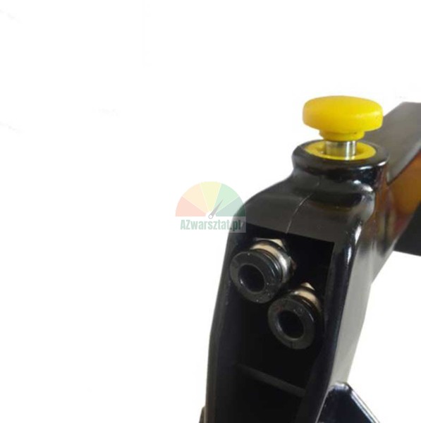 Detailní záběr na černou mechanickou součástku se žlutým tlačítkem a dvěma montážními otvory na bílém pozadí