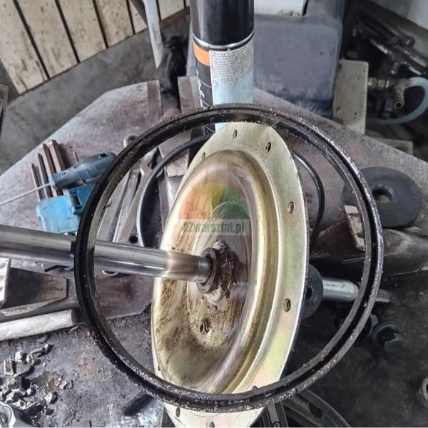 Detailní záběr na rozebranou mechanickou součást s kovovým kotoučem a hřídelí obklopenou dílenským nářadím